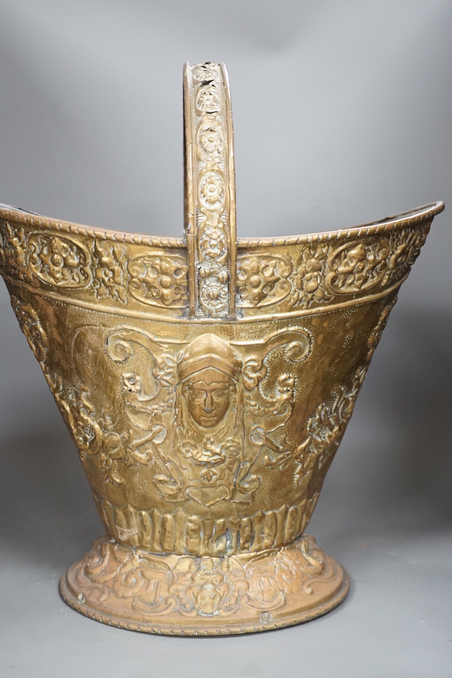 An embossed brass helmet coal bucket, 48cms high